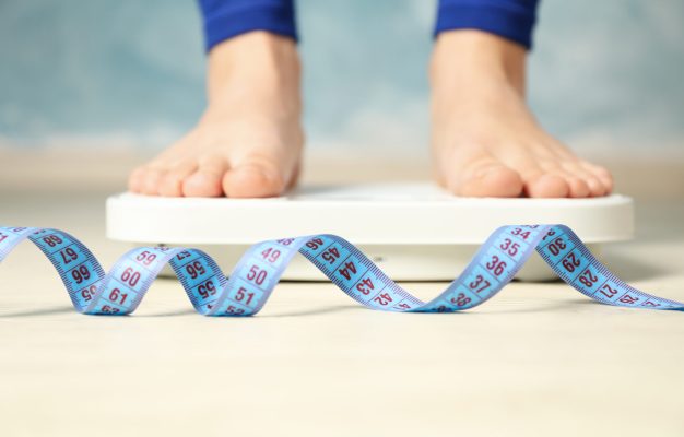 Woman stands on the scales. Measuring tape. Weight loss